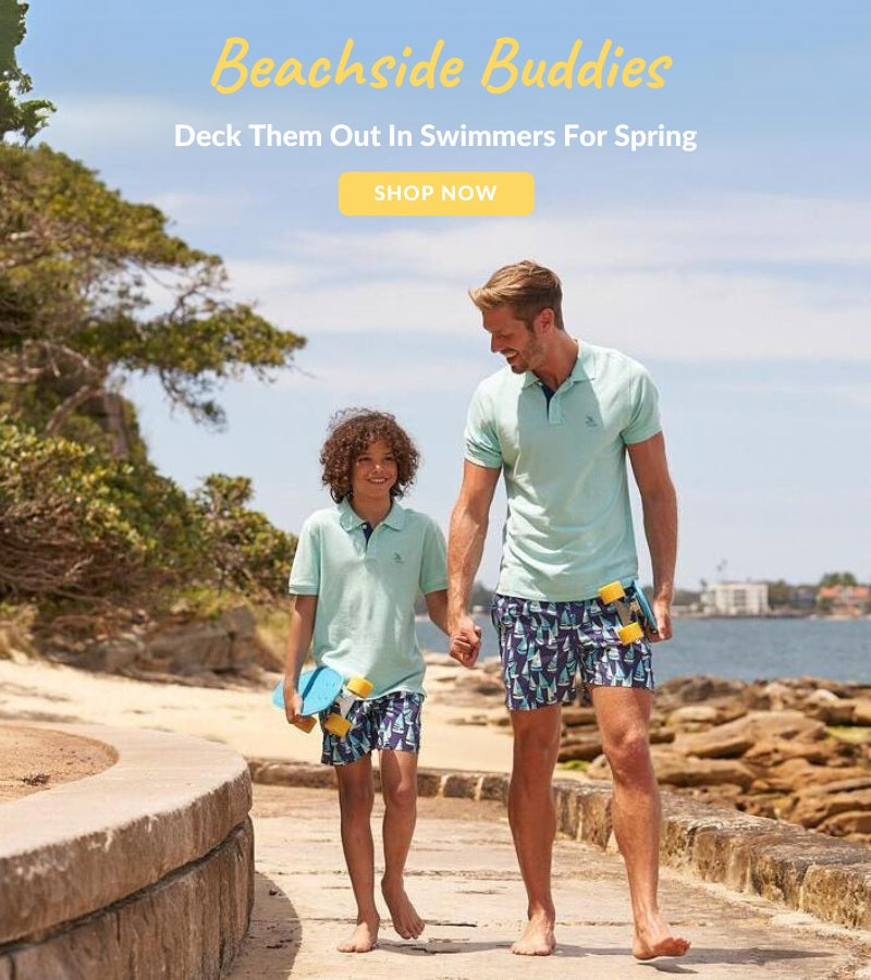 A man and his son walking down the beach in matching swimwear